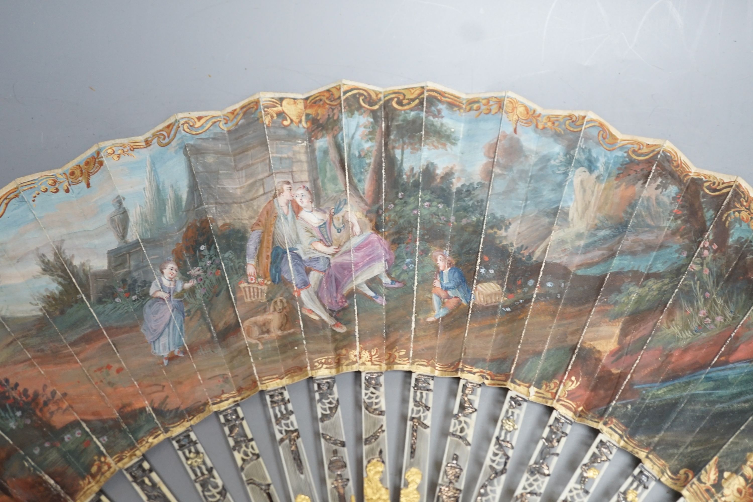 Two late 18th/early 19th century French gilded and silvered ivory and painted paper leaf fans